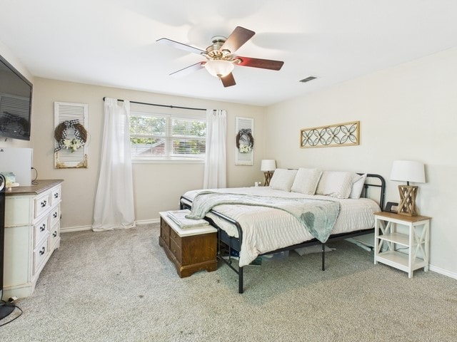 bedroom with baseboards, a ceiling fan, visible vents, and light colored carpet