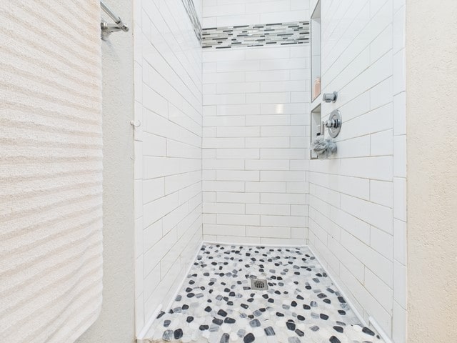 bathroom featuring a textured wall and a stall shower