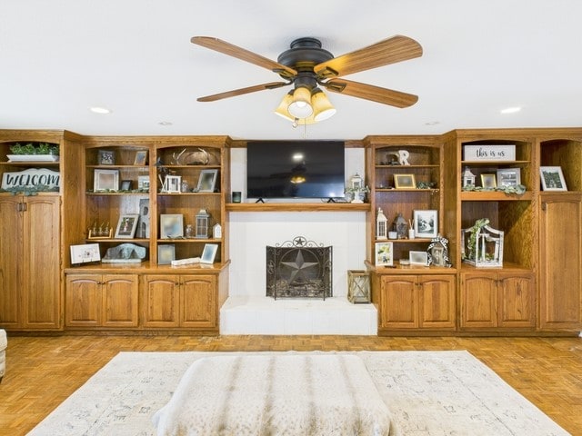 living room featuring a ceiling fan, a fireplace with raised hearth, and recessed lighting