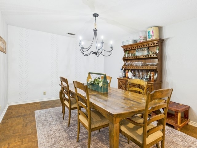 dining space featuring baseboards, a chandelier, and visible vents