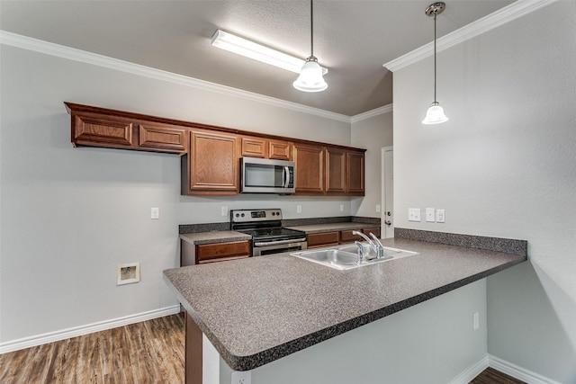 kitchen with stainless steel appliances, a peninsula, a sink, dark countertops, and baseboards