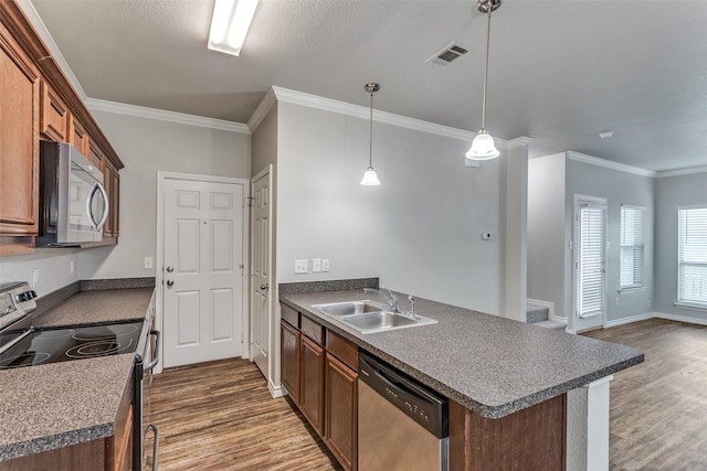 kitchen featuring stainless steel appliances, a peninsula, a sink, dark wood-style flooring, and visible vents
