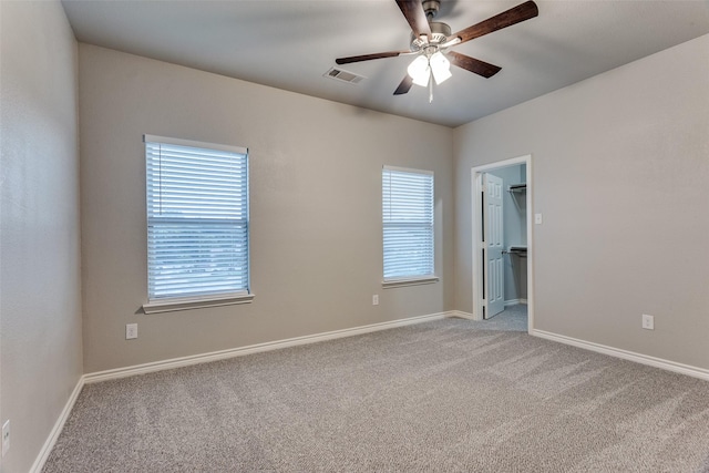 carpeted empty room with baseboards, a ceiling fan, and visible vents