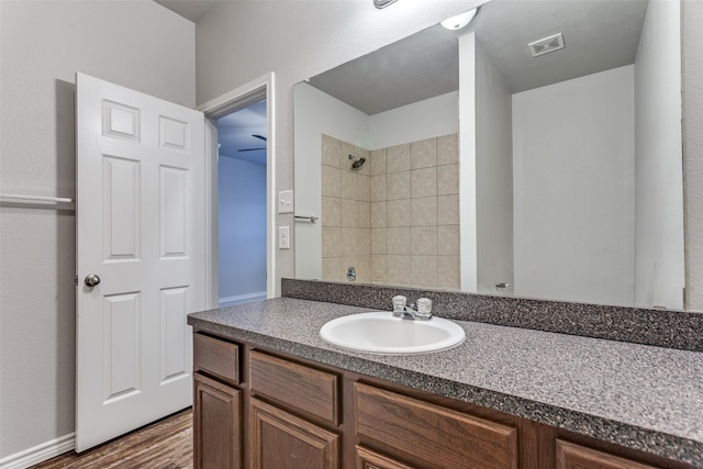 bathroom featuring wood finished floors, visible vents, vanity, and tiled shower