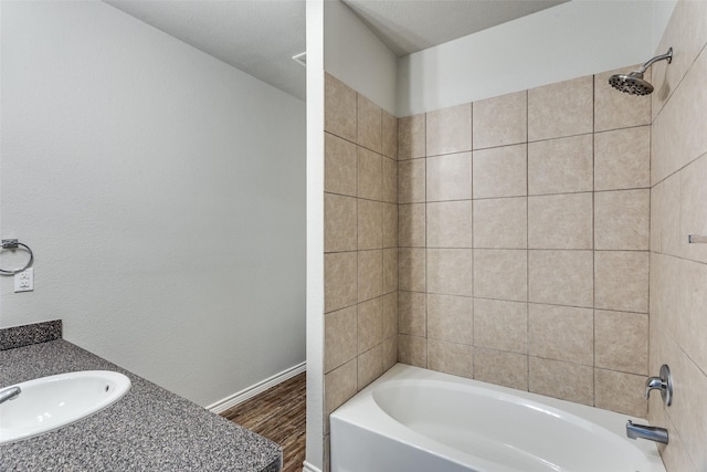 bathroom with baseboards, wood finished floors, a sink, and shower / tub combination