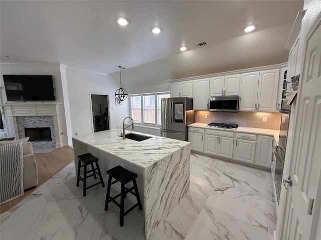 kitchen with a sink, decorative backsplash, appliances with stainless steel finishes, open floor plan, and white cabinetry