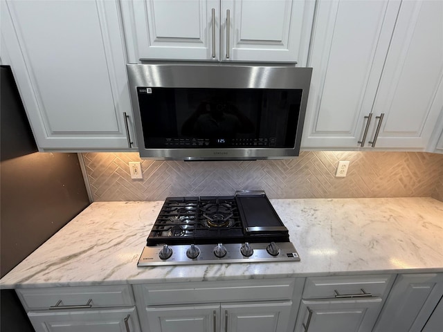room details featuring white cabinets, light stone countertops, backsplash, and appliances with stainless steel finishes