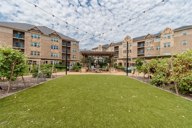 view of property's community featuring a lawn, a pergola, and a patio area
