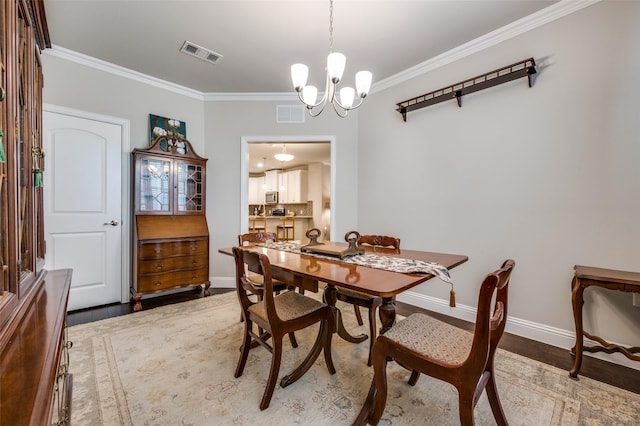dining space with baseboards, wood finished floors, visible vents, and crown molding