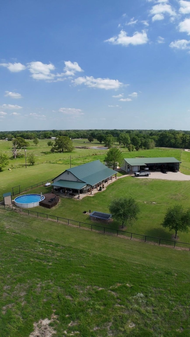 view of property's community featuring a rural view, a yard, and fence