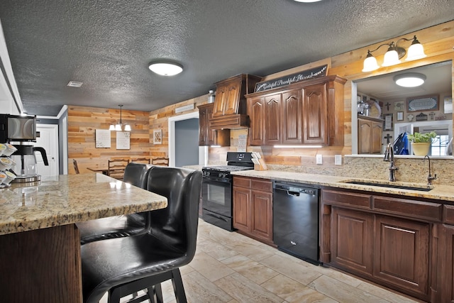 184 Wildflower Trl, Weatherford, TX 76087 - kitchen featuring a sink, visible vents, wooden walls, a breakfast bar, and black appliances