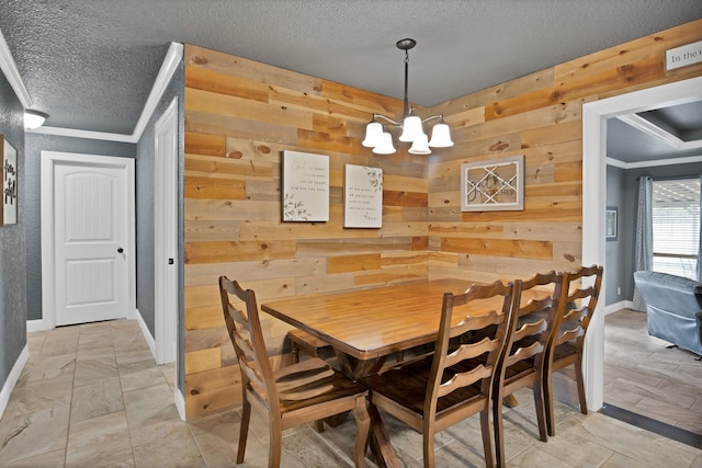 184 Wildflower Trl, Weatherford, TX 76087 - dining room with a textured ceiling, wooden walls, an inviting chandelier, baseboards, and ornamental molding