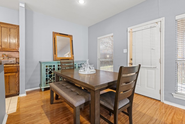 dining room with light wood-type flooring, a healthy amount of sunlight, and baseboards