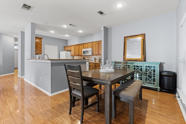 dining area with baseboards, visible vents, and light wood-type flooring