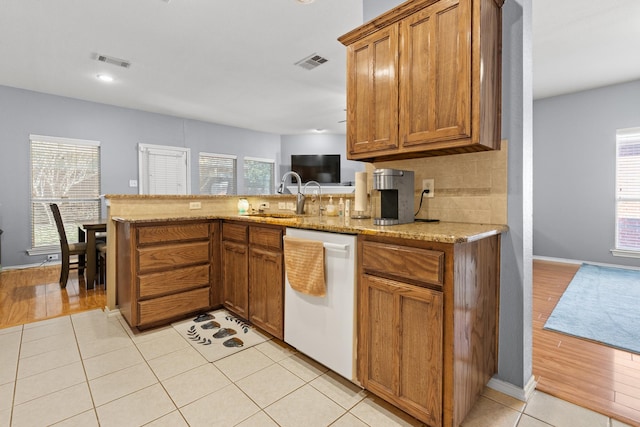 kitchen featuring brown cabinets, dishwasher, visible vents, and a sink