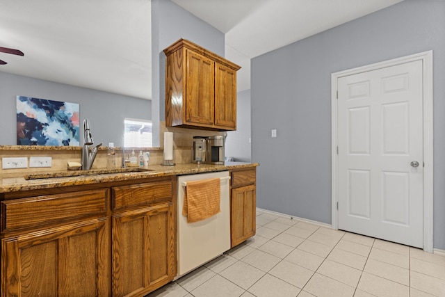 kitchen featuring a ceiling fan, a sink, white dishwasher, light stone countertops, and brown cabinetry