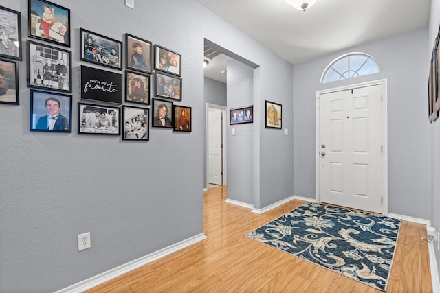 foyer entrance with baseboards and wood finished floors