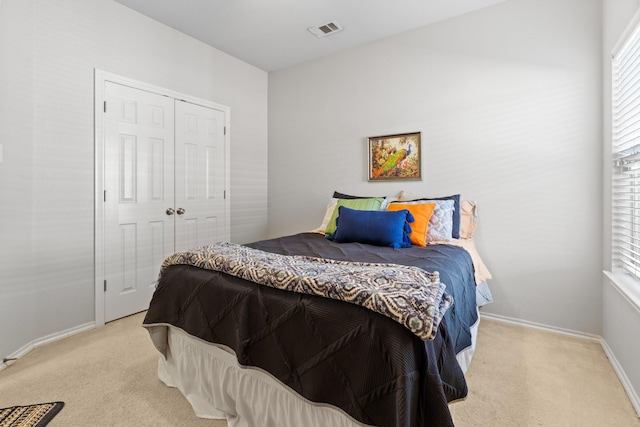 bedroom featuring baseboards, a closet, visible vents, and carpet
