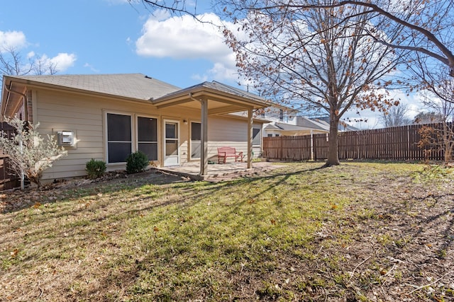 rear view of property featuring fence, a patio area, and a yard