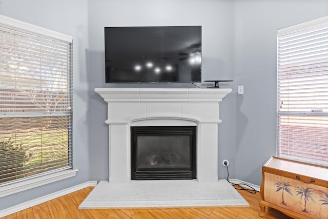 details with baseboards, wood finished floors, and a glass covered fireplace
