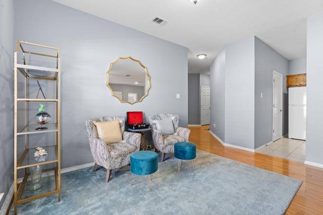 living area featuring baseboards, wood finished floors, and visible vents