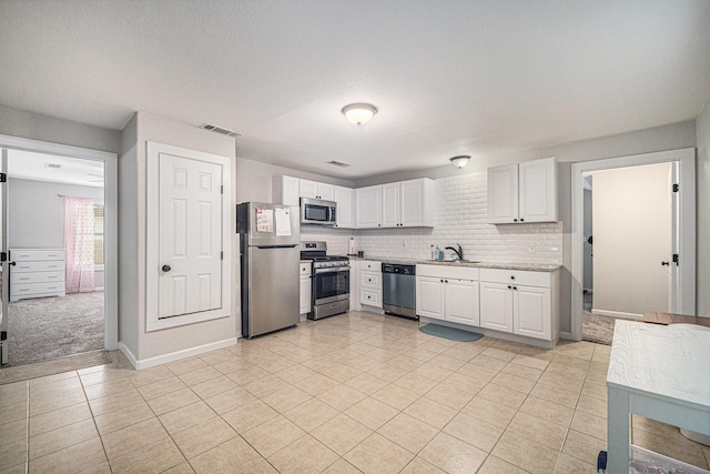 kitchen featuring light countertops, visible vents, a sink, appliances with stainless steel finishes, and white cabinetry