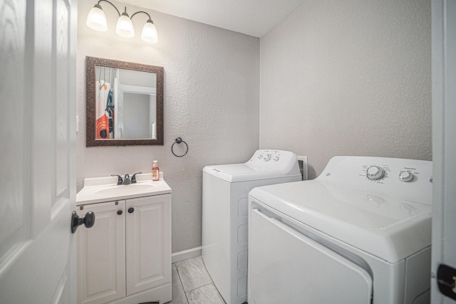 laundry area with a textured wall, washer and clothes dryer, marble finish floor, and a sink