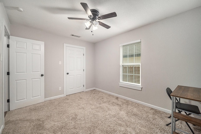 unfurnished office with visible vents, carpet flooring, baseboards, and ceiling fan