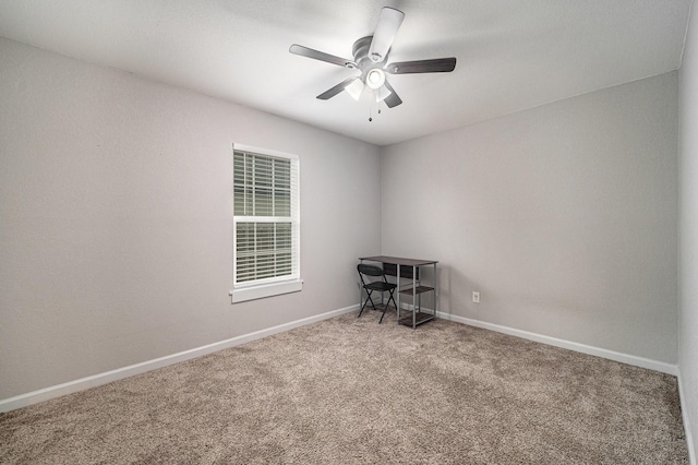 carpeted empty room featuring a ceiling fan and baseboards