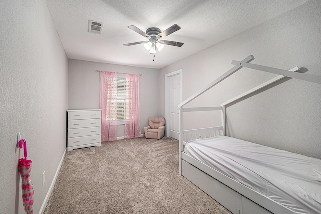 bedroom featuring ceiling fan, a textured wall, baseboards, carpet flooring, and visible vents