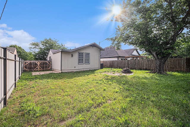rear view of house featuring a lawn and a fenced backyard