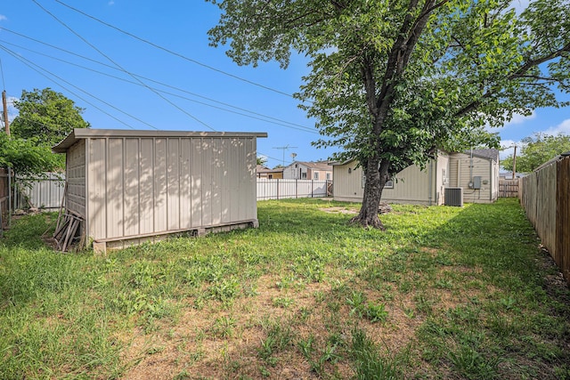 view of yard with a fenced backyard, an outbuilding, cooling unit, and a shed