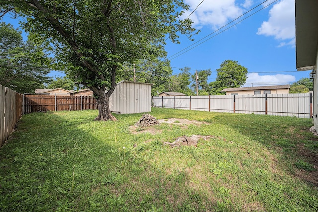 view of yard with a storage unit, an outbuilding, and a fenced backyard
