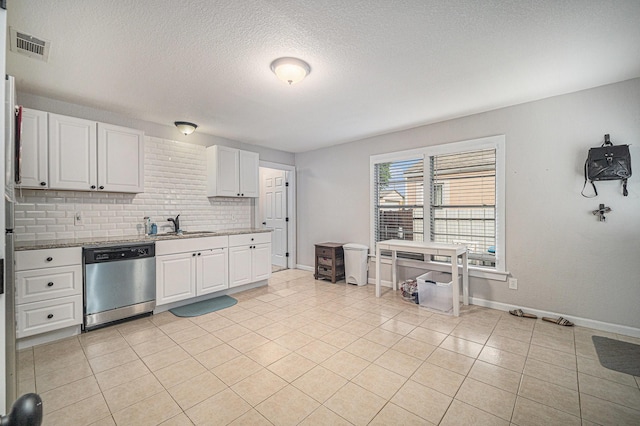 kitchen with stainless steel dishwasher, a textured ceiling, light tile patterned flooring, baseboards, and white cabinetry