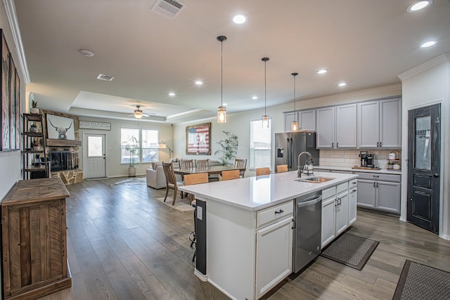 kitchen with a sink, open floor plan, stainless steel appliances, light countertops, and visible vents