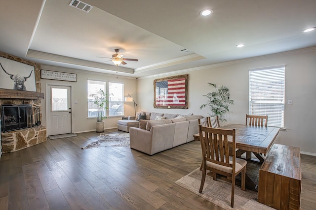 living room with a ceiling fan, a fireplace, ornamental molding, visible vents, and a raised ceiling