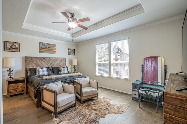 bedroom featuring a ceiling fan, wood finished floors, a raised ceiling, baseboards, and ornamental molding