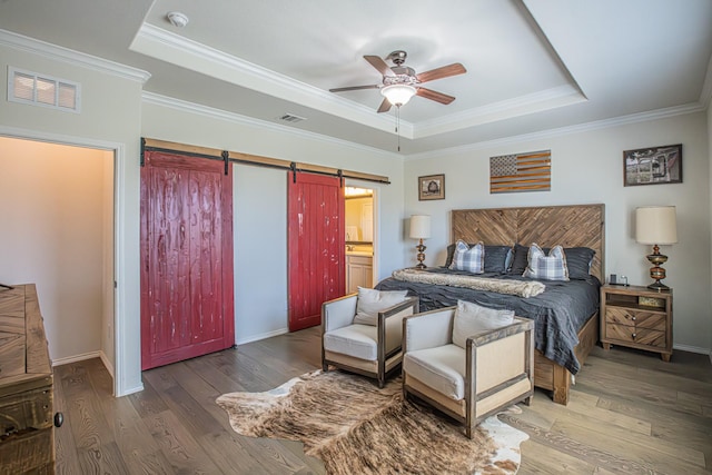 bedroom with visible vents, a raised ceiling, and a barn door
