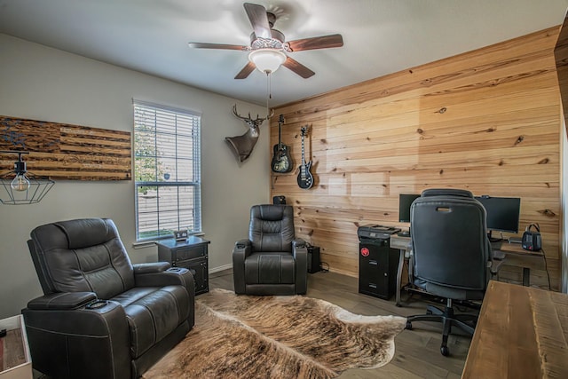 office space with ceiling fan, wood walls, and wood finished floors