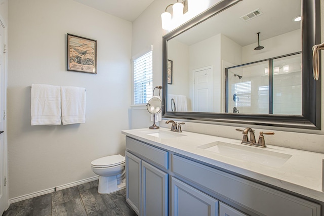 bathroom with wood finished floors, visible vents, a sink, and a stall shower