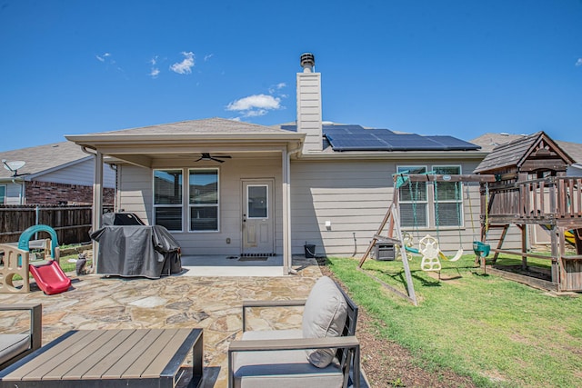 rear view of property featuring fence, a yard, solar panels, a patio area, and ceiling fan