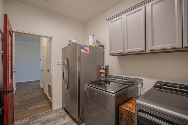laundry area featuring separate washer and dryer, baseboards, cabinet space, and wood finished floors