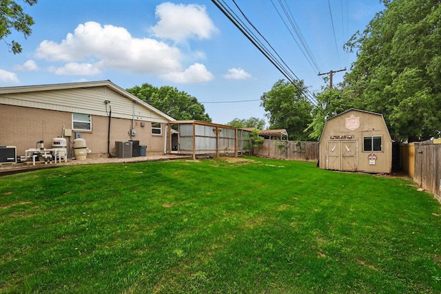 view of yard with a fenced backyard, an outdoor structure, central AC unit, and a shed