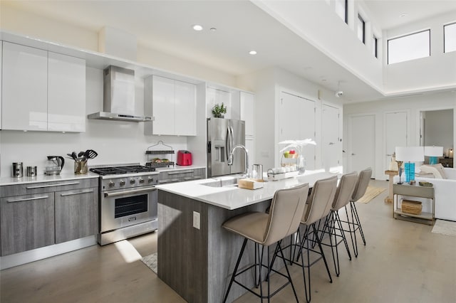 3923 Cole Ave Unit 303, Dallas, TX 75204 - kitchen featuring wall chimney range hood, a kitchen breakfast bar, a sink, a kitchen island with sink, and stainless steel appliances