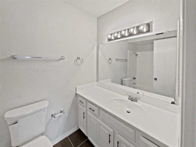 full bath with tile patterned floors, walk in shower, vanity, and toilet