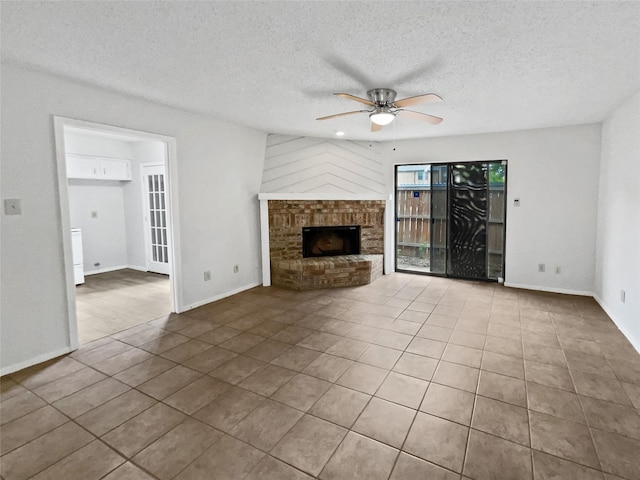 unfurnished living room featuring tile patterned floors, a textured ceiling, baseboards, a ceiling fan, and a brick fireplace