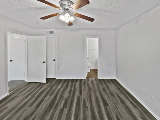unfurnished bedroom with wood finished floors, a textured ceiling, baseboards, ensuite bath, and visible vents