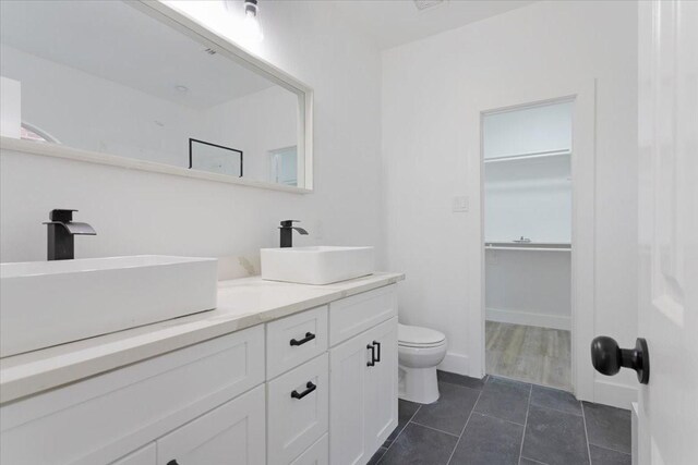 1941 Juniper Dr, Little Elm, TX 75068 - bathroom featuring toilet, tile patterned flooring, double vanity, and a spacious closet