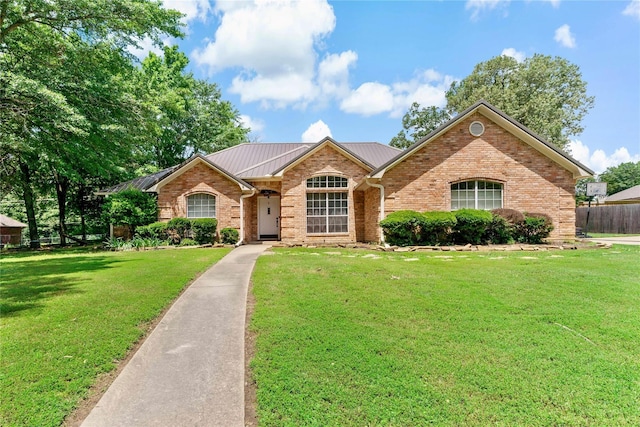 ranch-style house featuring fence, brick siding, a front yard, and metal roof