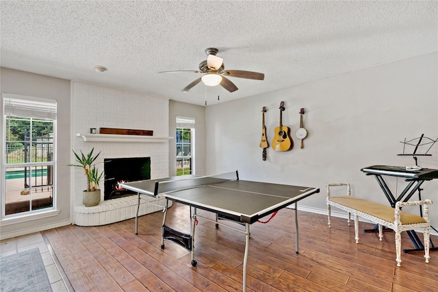 game room featuring plenty of natural light, a textured ceiling, ceiling fan, and wood finished floors